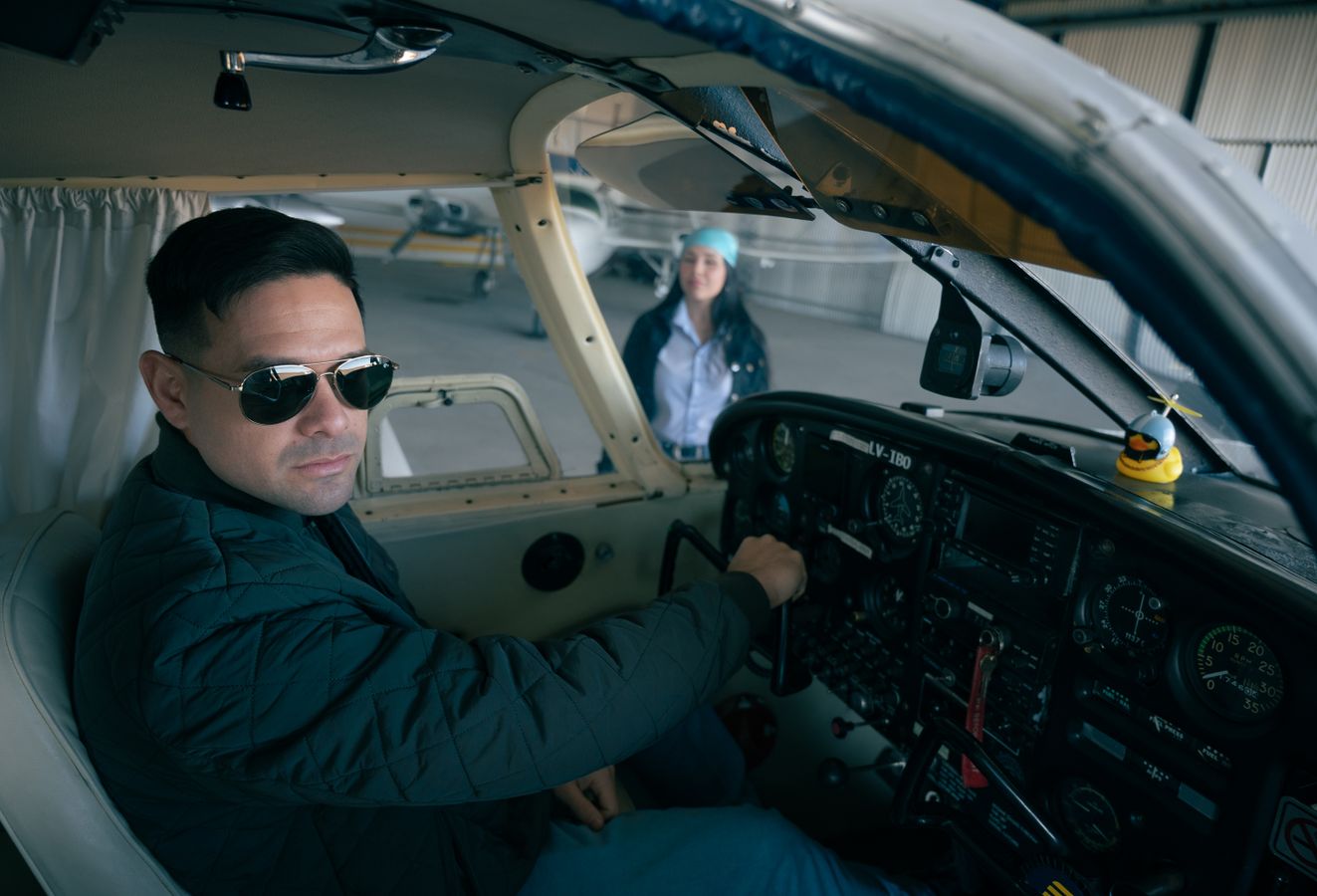 Pilot seated in a small-aircraft cockpit with another aviation professional nearby