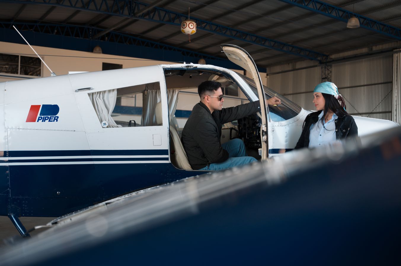 Two aviation peers discussing beside a small aircraft in a hangar